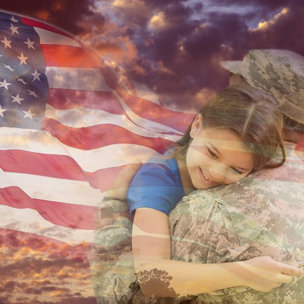 Little girl gives her military father a big hug overlay on dramatic sunset sky and waving American flag.