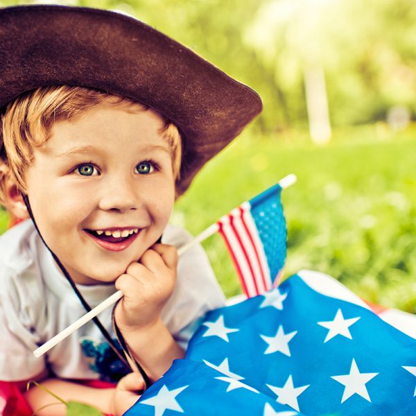 "Cute little cowboy laying on American flag, 4th of July - Independence day"